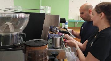 Mujer poniendo una cafetera detrás de la barra
