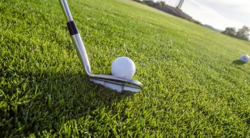 Palo y pelota de golf sobre césped.
